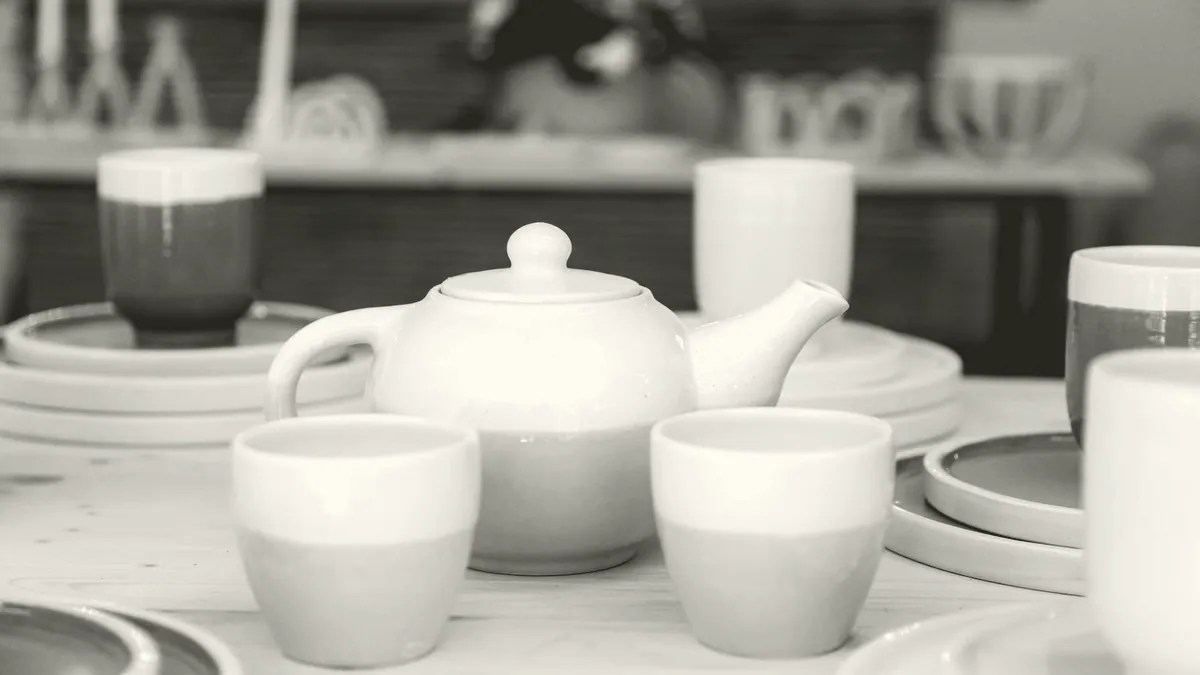 A teapot and two cups on a kitchen table.