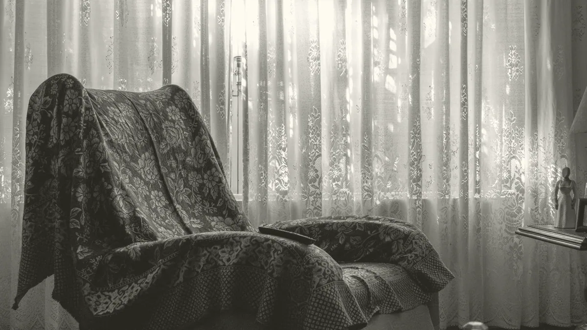 An armchair by a curtained window.