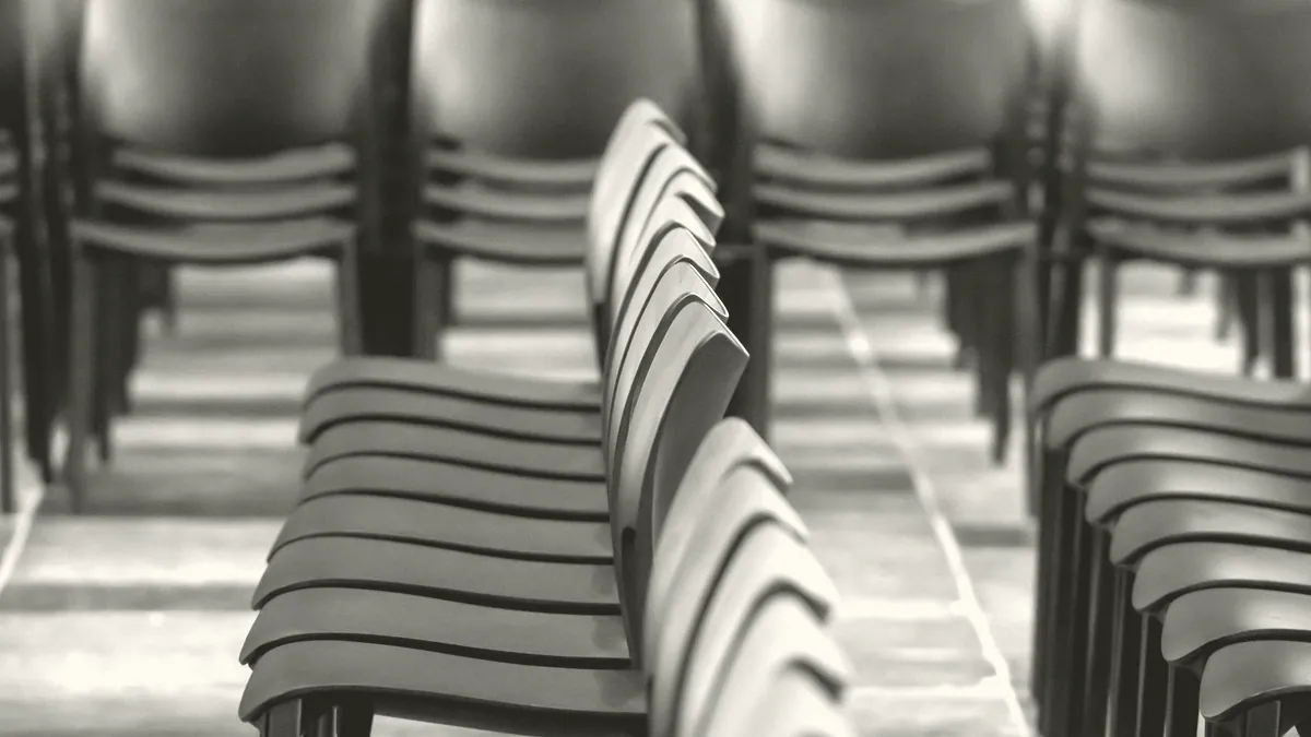 The inside of a village hall, chairs stacked.