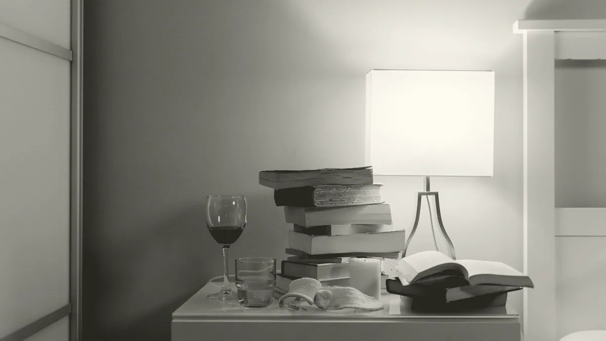 A stack of books beside a lamp.