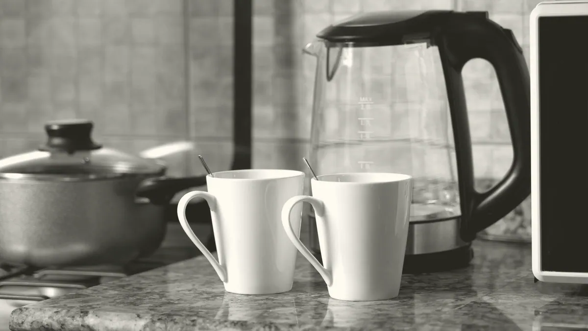 A kettle and mugs in a hall kitchen.